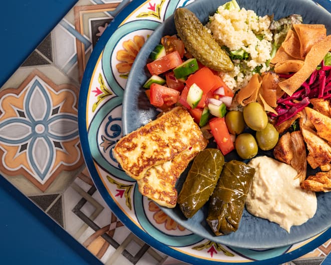 Loaded sharing portion of traditional Eastern Mediterranean Arabic food of hummus, olives, grilled chicken, halloumi, dolma, couscous, salad and pickles