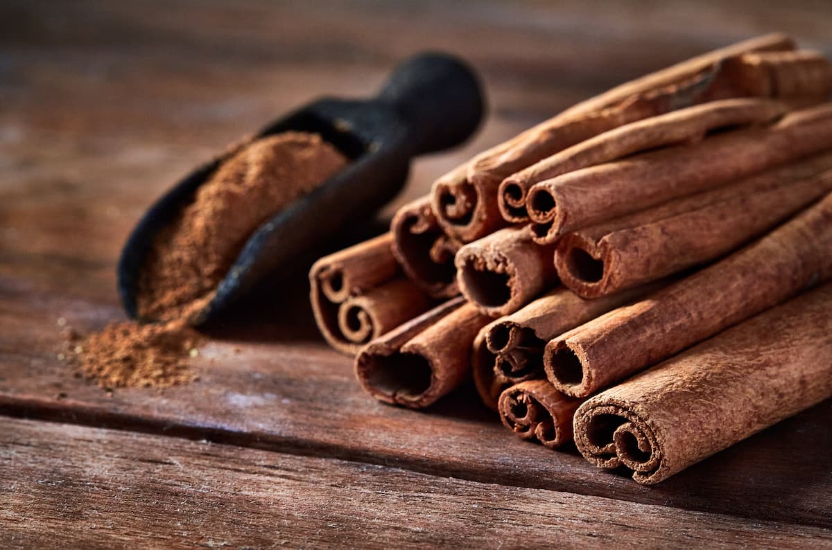 Stick cinnamon and cinnamon powder on rustic wooden table.