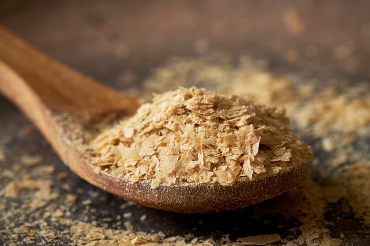 Closeup of nutritional brewers yeast flakes in wooden spoon