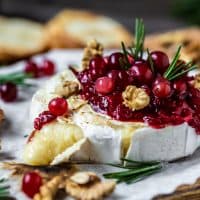 Baked Camembert brie with fresh rosemary and cranberry sauce. Gourmet appetizer. Breakfast, Food recipe background. Close up