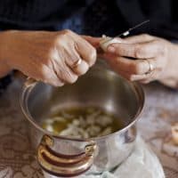 Hands of Grandma, putting onion in a pot for cooking