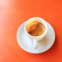 Espresso coffee in a white ceramic cup on an orange background