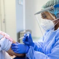 A woman doctor or nurse vaccinating a patient with a syringe