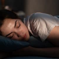 Portrait of beautiful young woman sleeping cozily on a bed in her bedroom at night. Close-up