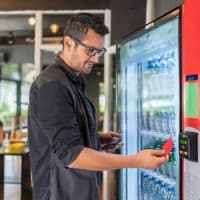 Man Selects Drink At Vending Machine And Pays With Credit Card