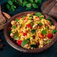 African couscous in the tagine, with spices and herbs on a dark wooden background