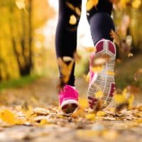 Close up of runner’s feet running in autumn leaves training exercise