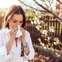 Attractive young adult woman coughing and sneezing outdoors. Sick people allergy or virus influenca concept.