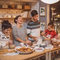 Mother with children in kitchen preparing Christmas cakes