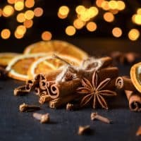 Traditional Christmas spices with dried orange slices on black background with defocus lights