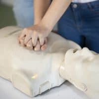 Close up of hand compressions on a CPR dummy in training class.