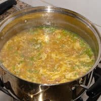 Seasonal vegetable soup with potatoes, ham, onions, eggs, peas, corn, and tomatoes