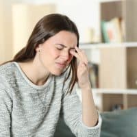 Woman scratching itchy eye at home