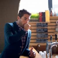 Shot of a handsome young man at the bar covering his mouth