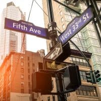 Street sign of Fifth Ave and West 33rd St at sunset in New York City - Urban concept and road direction in Manhattan downtown - American world famous capital destination on warm dramatic filtered look